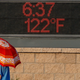 A pedestrian uses an umbrella to get some relief from the sun as she walks past a sign displaying the temperature on June 20, 2017 in Phoenix.